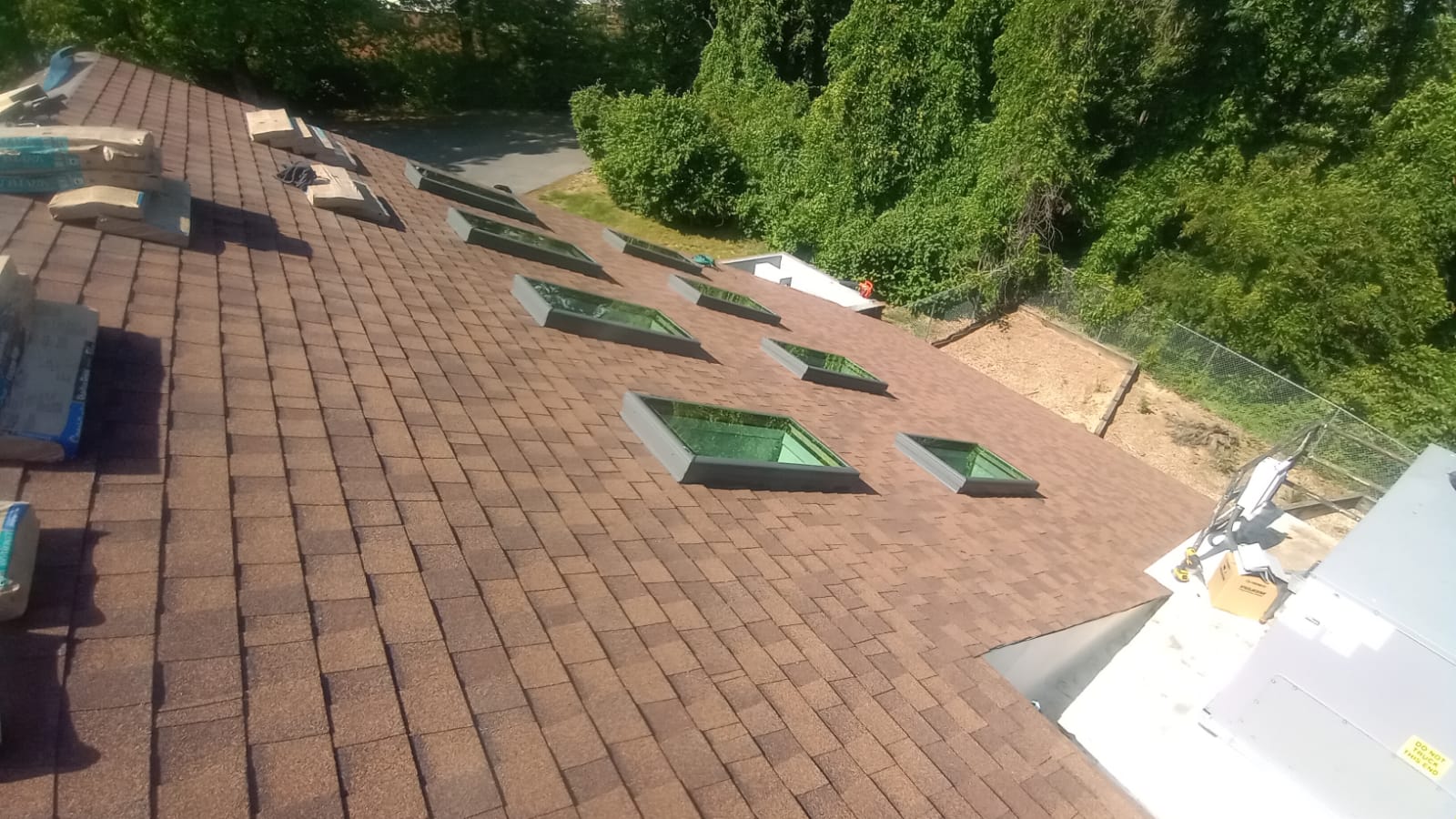 Newly installed roof with skylights and roofing materials staged for the finishing stages