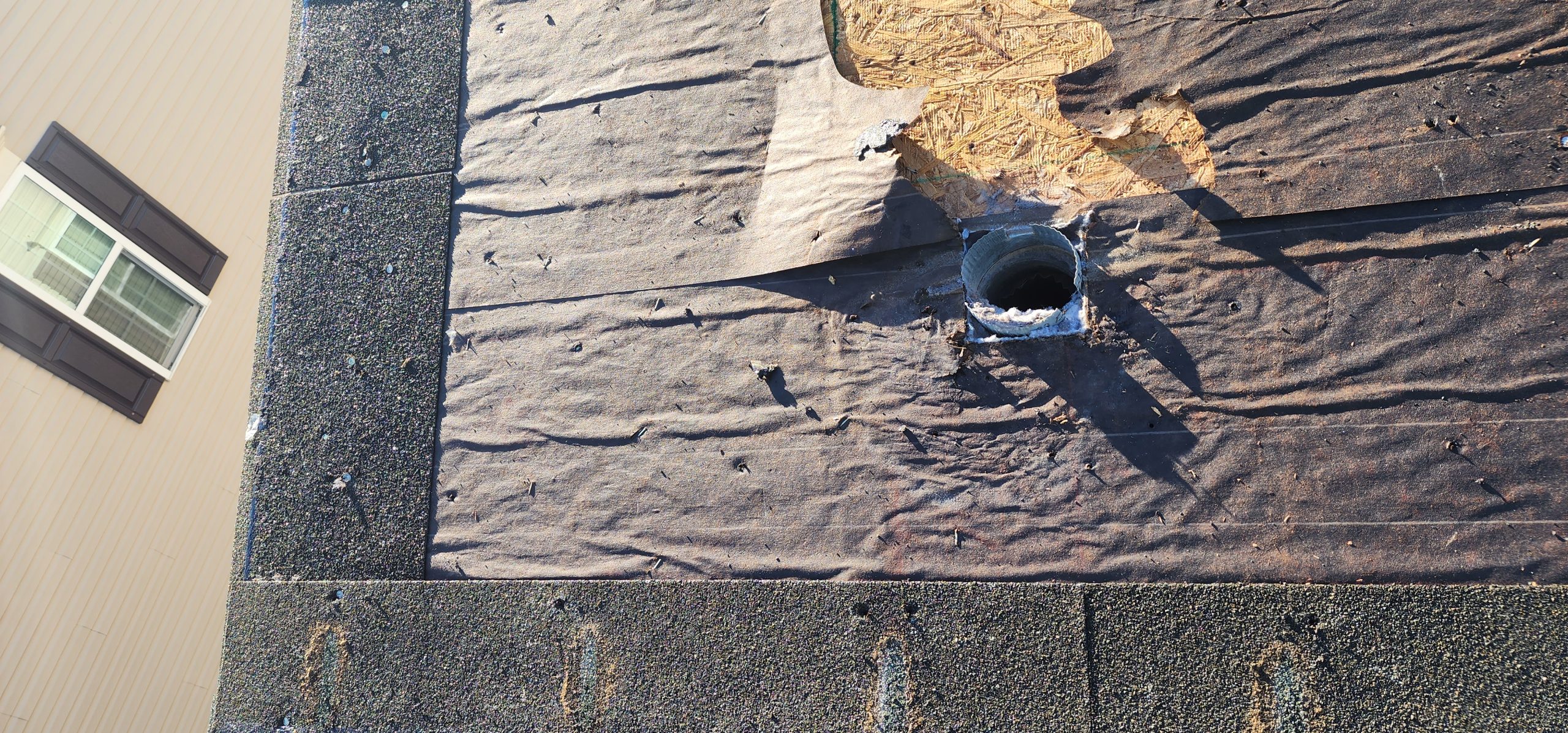 Roof deck exposed during a roof replacement, underlayment being removed before new shingles go on