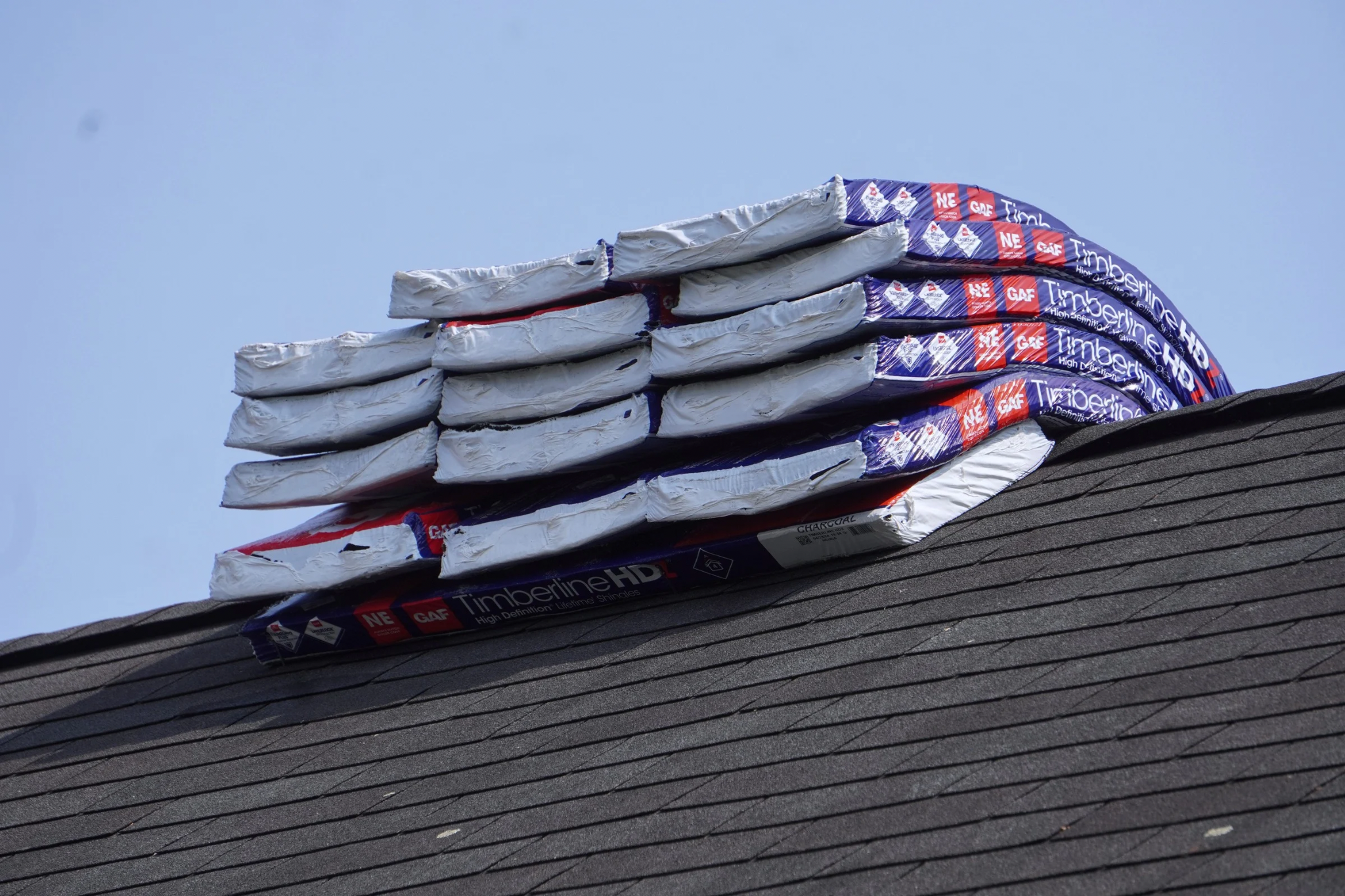 Shingle bundles staged on a roof edge ahead of installation
