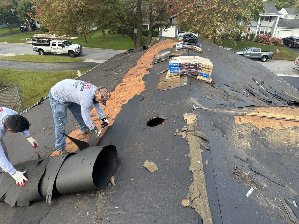 Crew stripping the old roof covering back along the ridge during a tear-off