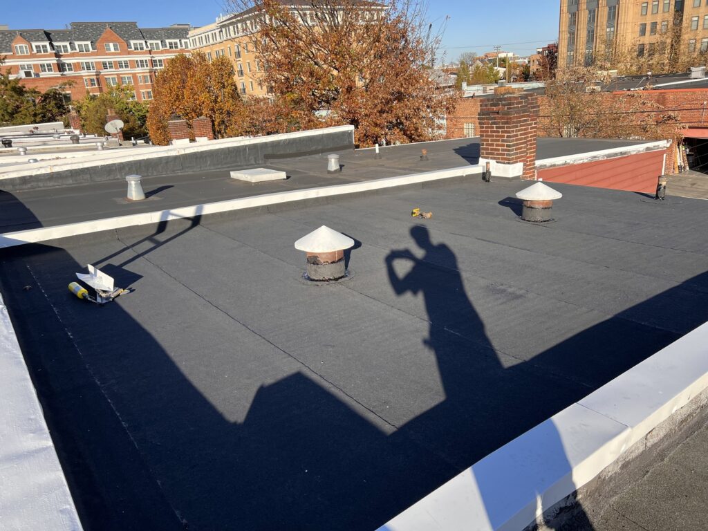 Finished torch-down flat roof with new vent caps and a clean white parapet edge in Alexandria, Virginia