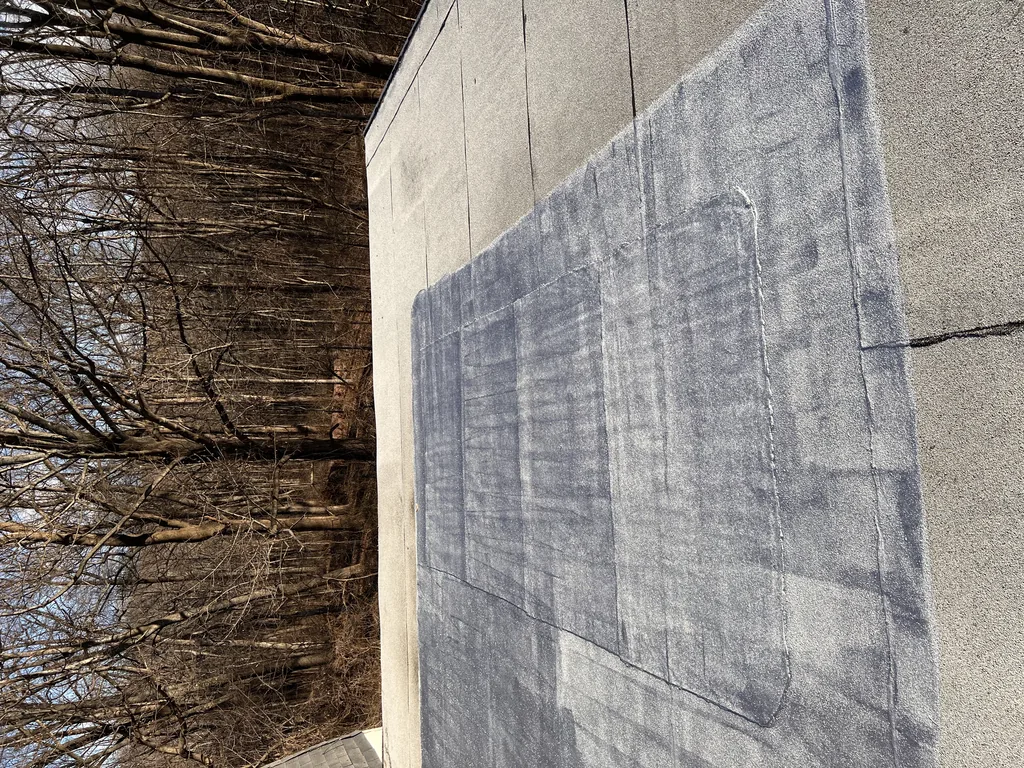 Coated flat roof section meeting a masonry parapet wall