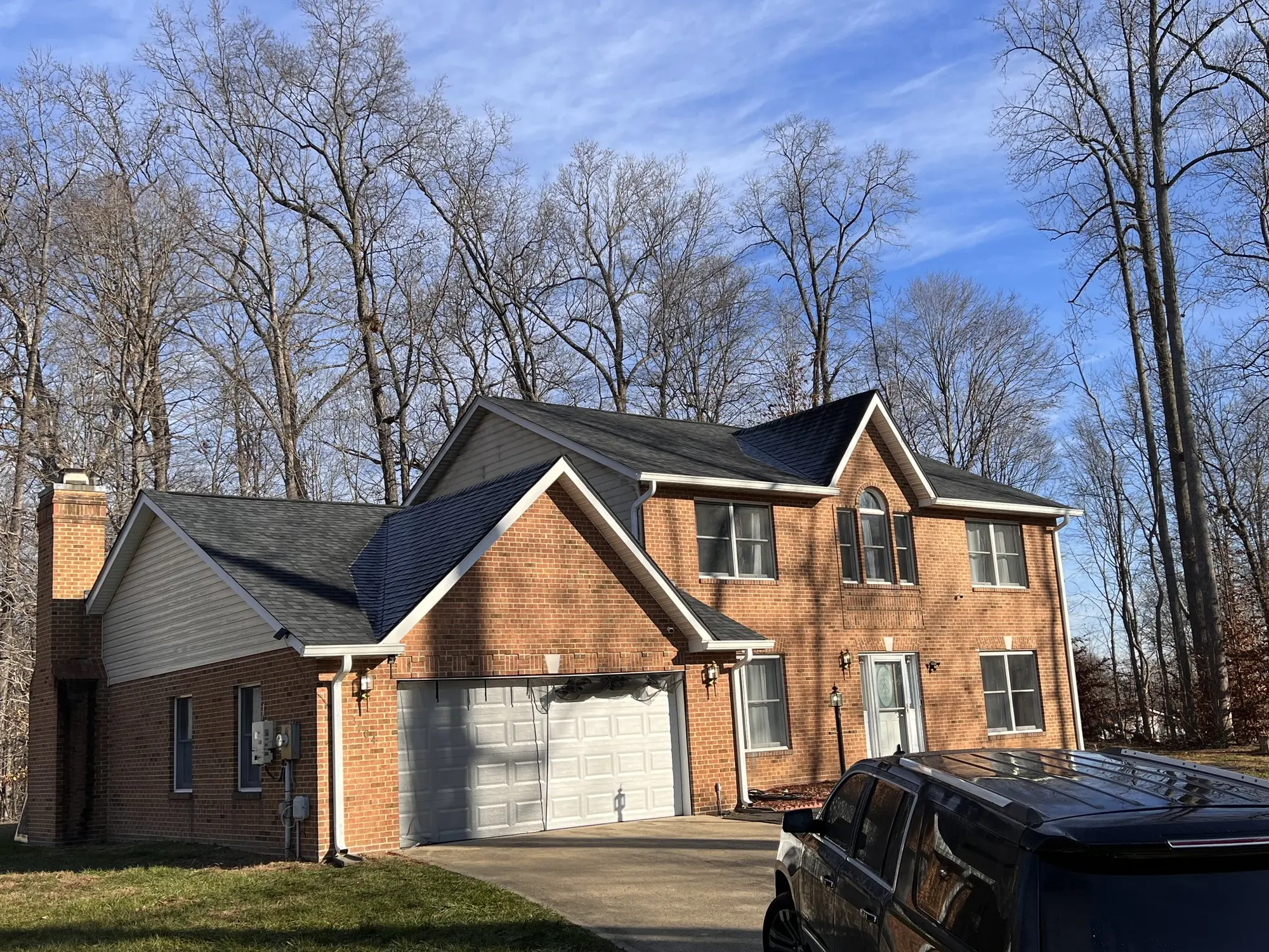 Brick home in Bethesda, Maryland with a completed dark architectural shingle roof under a clear winter sky
