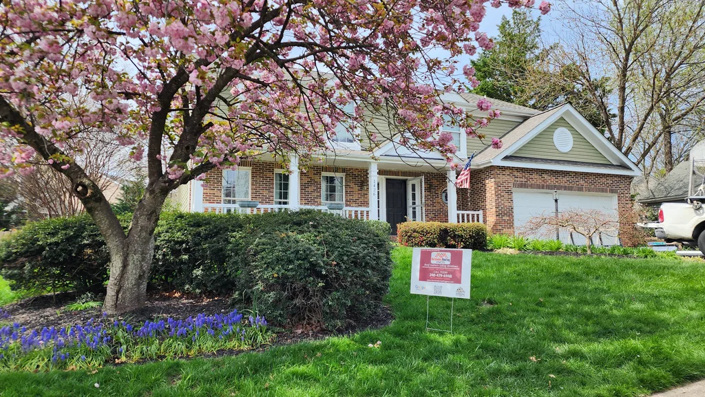 Brick home in North Potomac, Maryland with a completed roof, photographed in spring beside a flowering tree