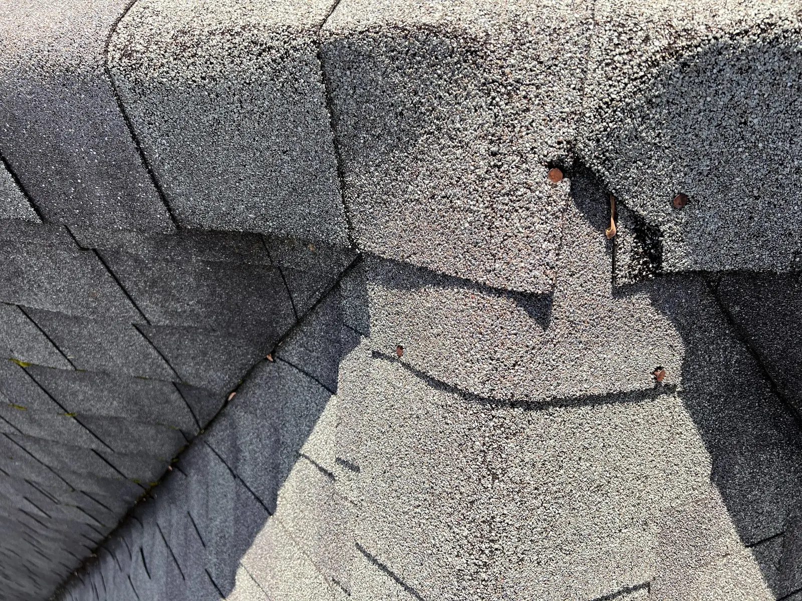 Torn and lifted shingles beside a roof valley, documented during a repair inspection