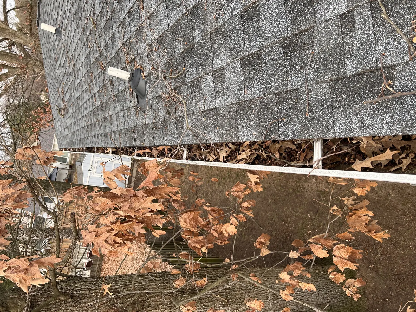 Gutter run packed with fallen leaves and debris before cleaning