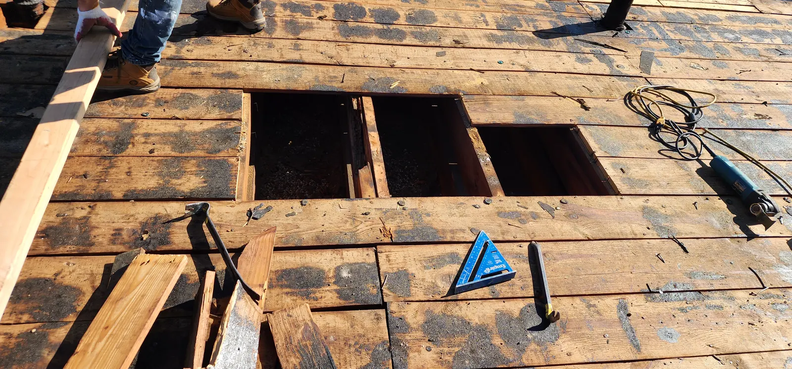 Roof deck repair in progress with damaged sections of decking cut out and replaced