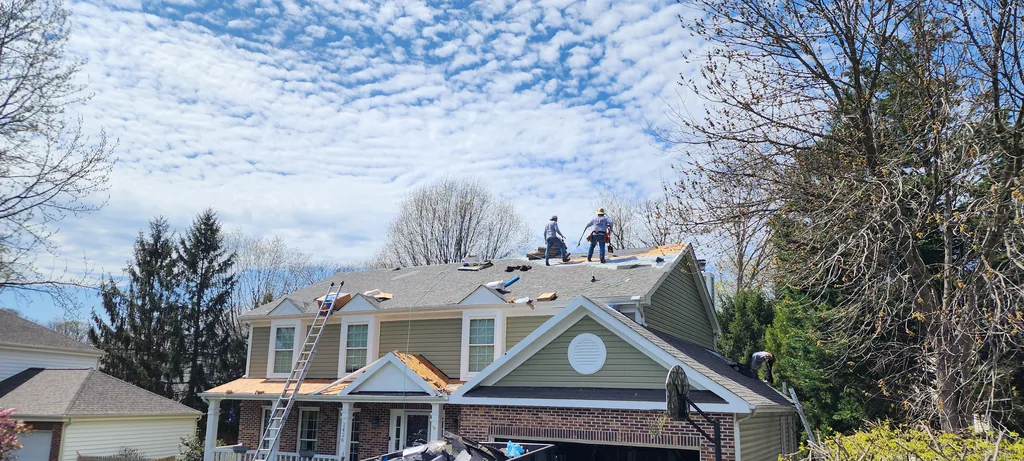 Hernandez Roofing Pros crew working on a roof replacement, with a ladder and debris container set up on site