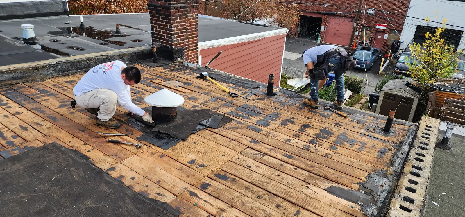 Hernandez Roofing Pros crew members working across the roof during tear-off of the old system