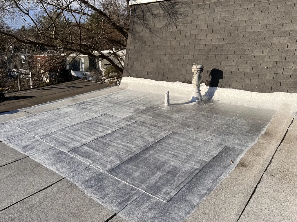 White-coated flat roof with a vent stack, finished across the full roof plane